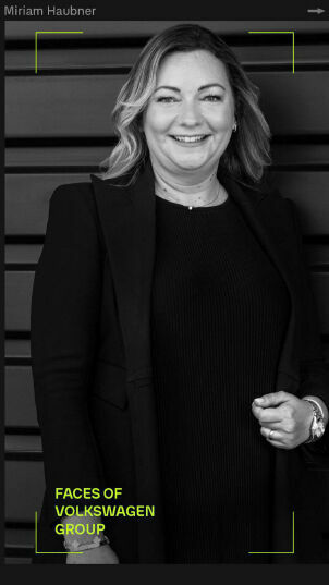 Porträt von Miriam Haubner, lächelnd, in einem schwarz-weiß Foto, gekleidet in einem Kleid und einem Blazer, mit dem Titel 'Faces of Volkswagen Group'.