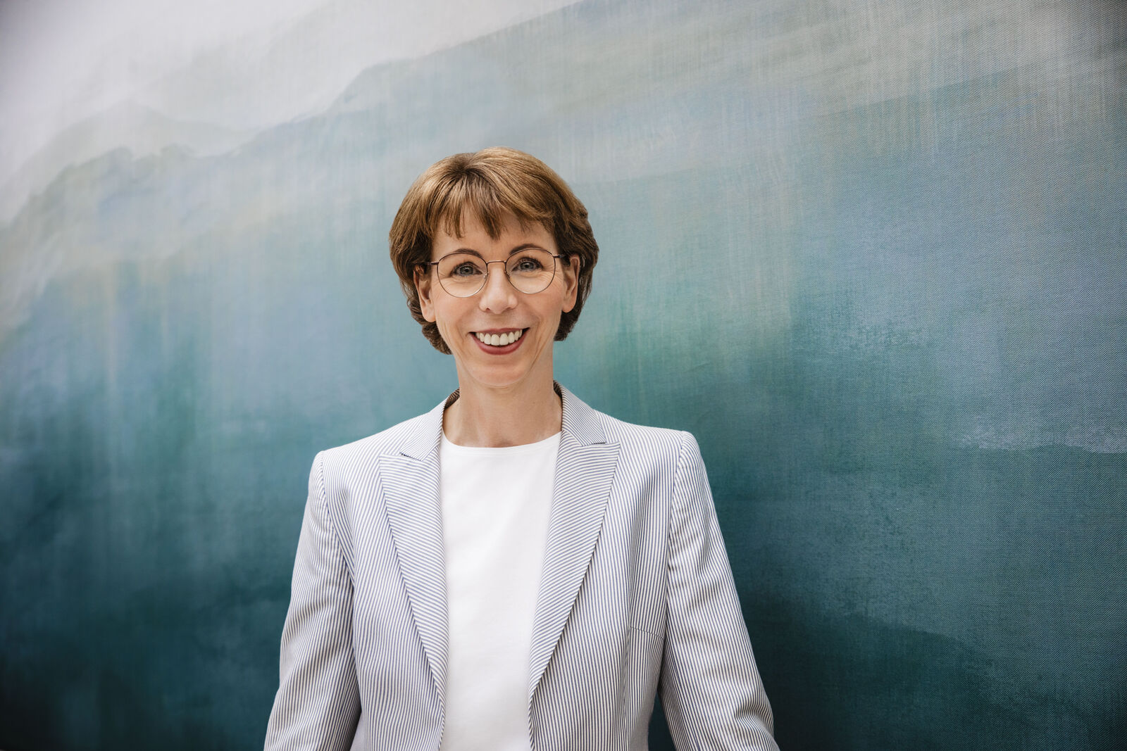 Hauke Stars, Board Member at Volkswagen Group for IT, in front of a dark blue painting with different shades.